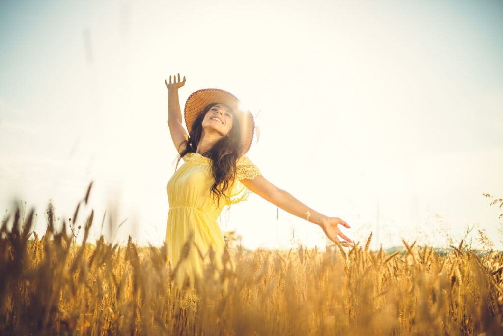 Mulher celebrando no campo representando salmos de gratidão por uma conquista alcançada