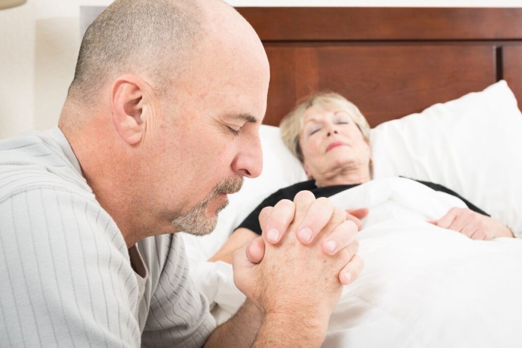 Homem orando ao lado de pessoa enferma representando salmos para oração e cura
