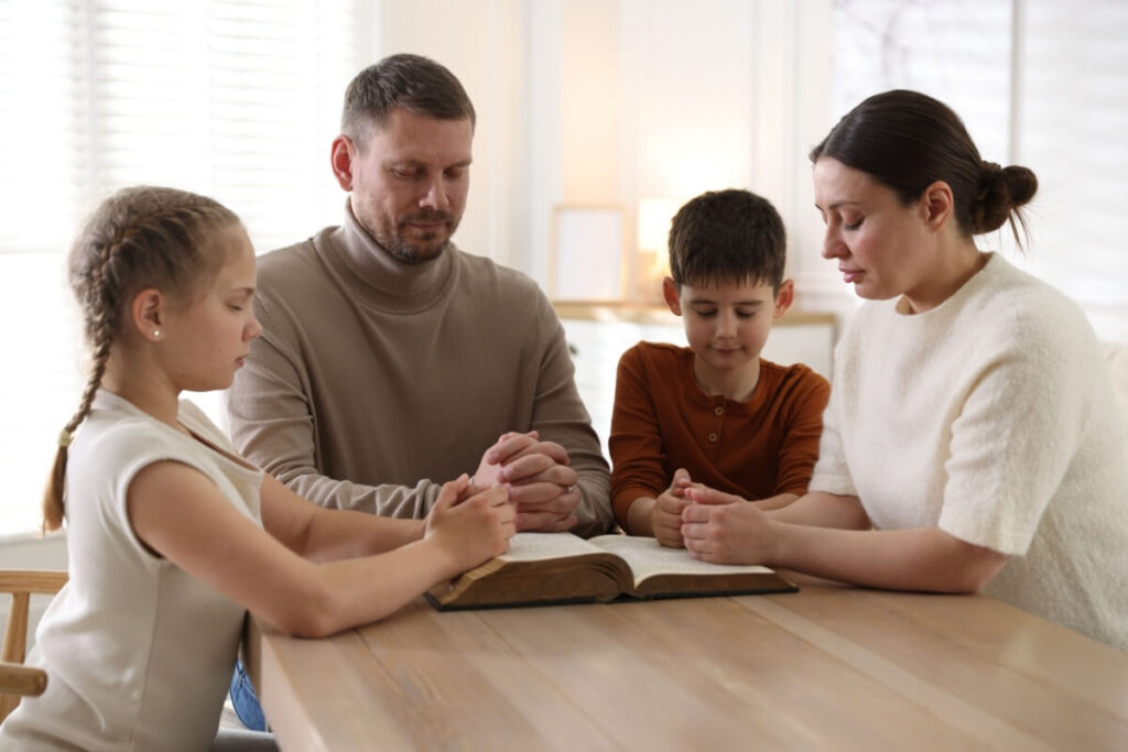 Família reunida em oração lendo a Bíblia com salmos poderosos para orar pelos filhos